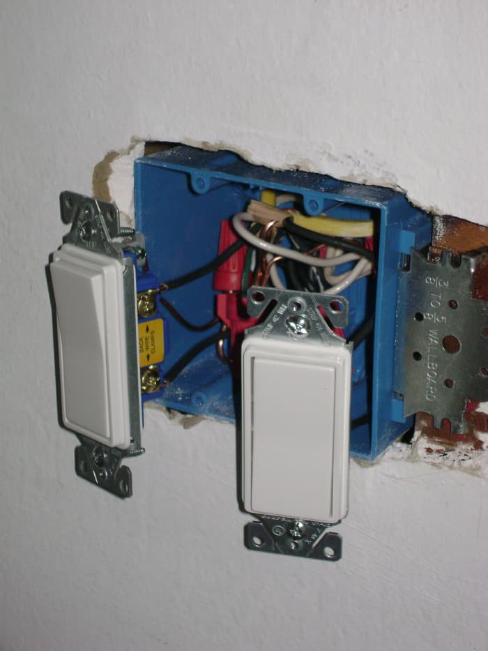  Deux interrupteurs d'éclairage s'insèrent dans une boîte de sortie à deux bandes. 
