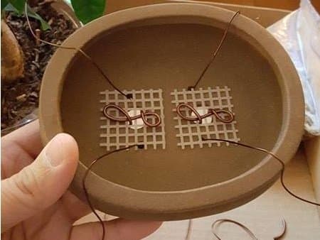 The completed preparation of the pot. Not, other than the drainage holes are smaller holes for anchor wires. These can be used to hold the root ball in place when repotting.
