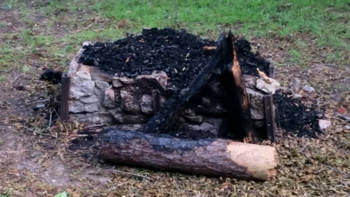 This stone-and-block fireplace may not be pretty, but it does elevate fuel away from the soil. And the charred logs show that there was lots of water to extinguish the fire when needed.