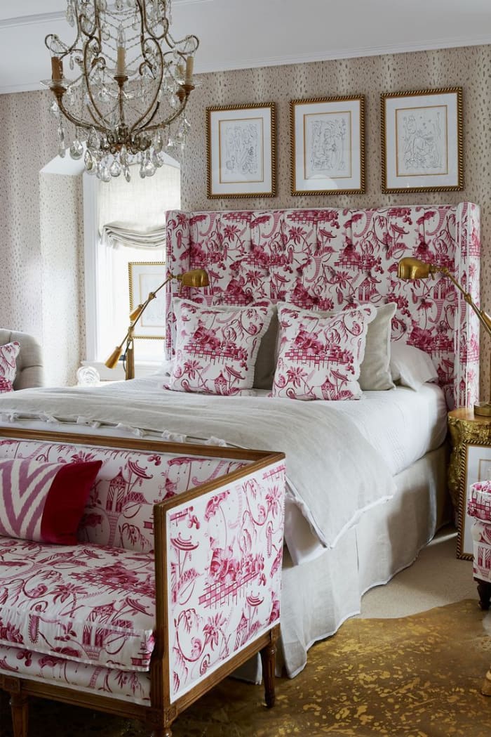 A vintage chandelier and brass table lamps give the bedroom a French flair.
