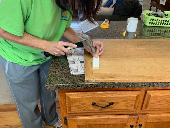 Putting a starter nail in the top rail board to make it easier to install. It was easier to start the nail on the counter rather than on the horizontal top rail.