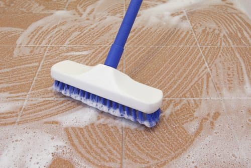 Scrub stone, ceramic or porcelain tiles with a stiff brush and heavy-duty cleaner. Consider purchasing a steam cleaner or hire a professional.