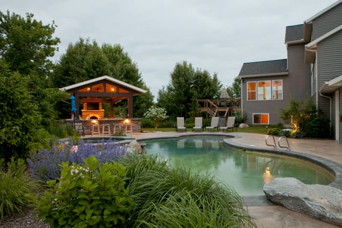 Nepeta blooms a profusion of purplish blue flowers on the pool edge. Companion plants like hydrangea and ornamental grasses help round out the look of the landscape with minimal maintenance.