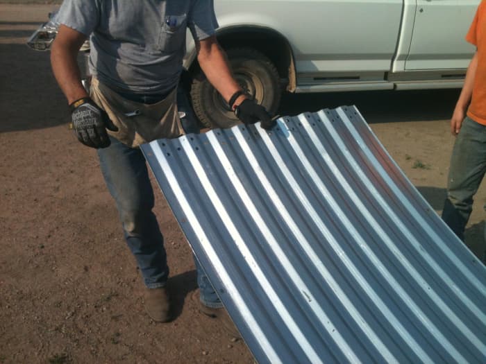 A punch is inserted through bolt holes in the wall sheets, providing a handle for dragging and lifting.