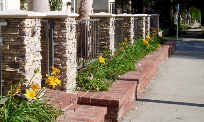 Day lilies planted in a Mediterranean style garden, with stone pillars and brick planter boxes. Ice plants are also commonly used with this style.