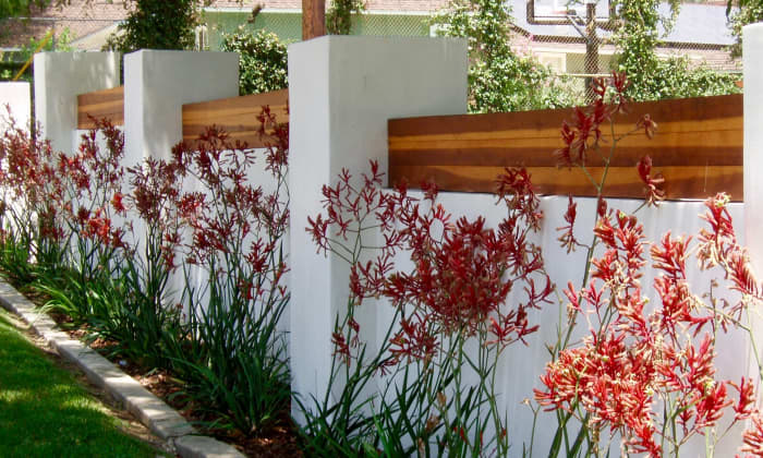 This planting follows along a wall that protects the house behind it. Its line and color match the decorative wood atop the wall and together they keep the eye traveling along the sidewalk area in front.