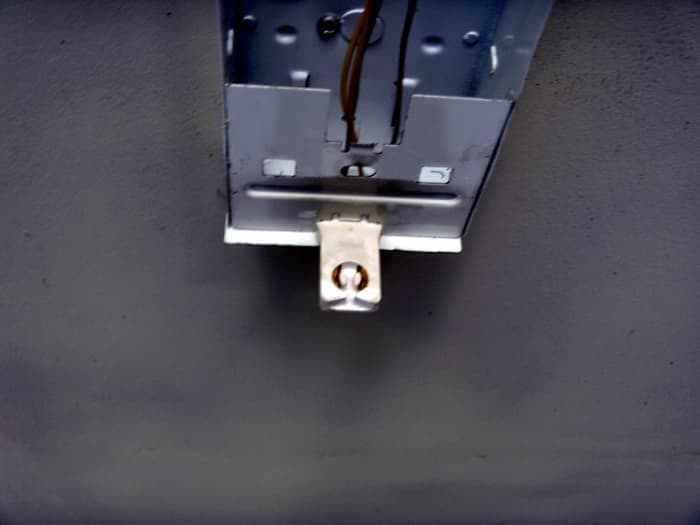A typical tombstone on a shop light. It is removed by spreading the sides of the fixture slightly, dropping the metal piece across the center, and sliding the tombstone out.