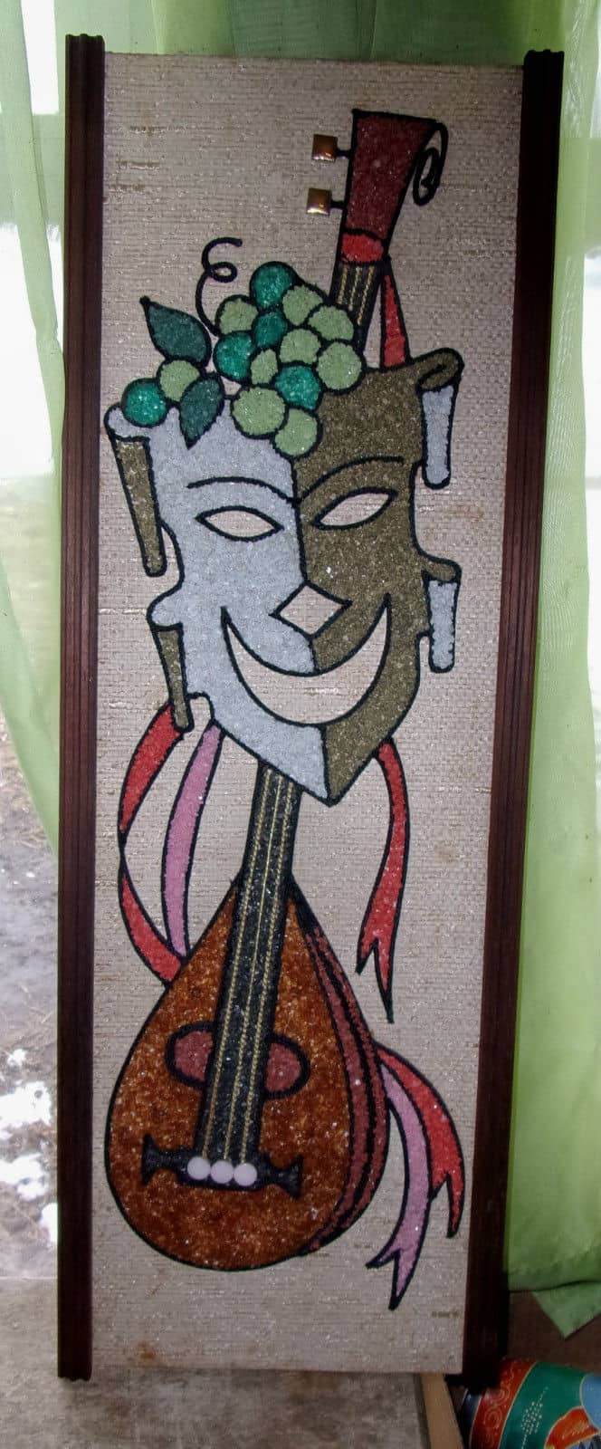 This is a 1960s vintage mid-century modern pebble or gravel art. Comedy mask with a lute, 24" x 8 1/2" in wooden frame.