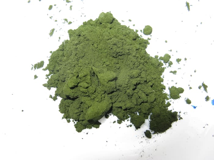 This is methylene blue powder. On the right, the green powder has dissolved in water drops and become a blue solution.