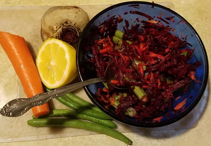A deliciously colorful beet salad posed for this photograph alongside some of the ingredients that gave themselves to its creation.