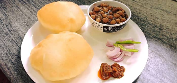 Instant bhature served with pindi chole, mango pickle, sliced onions, and green chillies