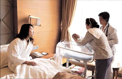 A woman watches a nanny care for her newborn baby as she continues her 30 day bed-rest during Sitting The Month
