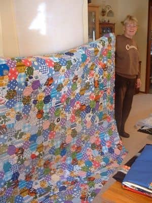 Margaret (student) shows the hexagon quilt she completed from the many hexagons made by her mother from family scrap fabrics.