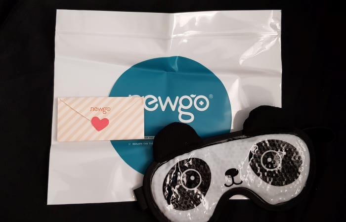 The items inside the packaging of the Newgo hot and cold therapy gel eye mask. A panda eye mask, a freezer safe sealing bag to store the mask in, a sweet note from the manufacturer.