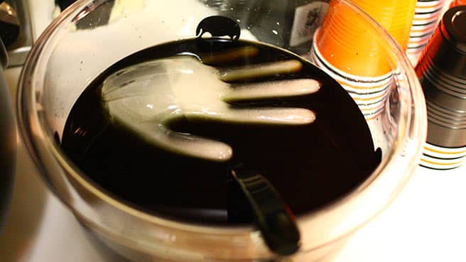 Make your own black Halloween party punch with an icy floating hand.