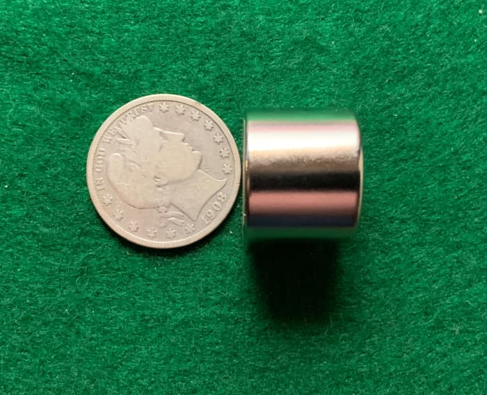 Using a strong Alnico magnet to see if a coin sticks to the magnet. This genuine silver Barber half dollar is not attracted to the magnet.