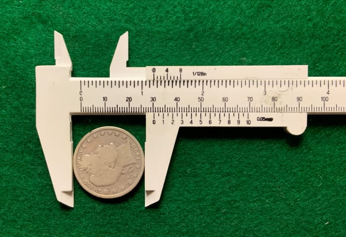 Measuring the diameter of a genuine Barber half dollar coin. The mint specified diameter is 30.6mm. The measured value is 30.5mm—close enough.