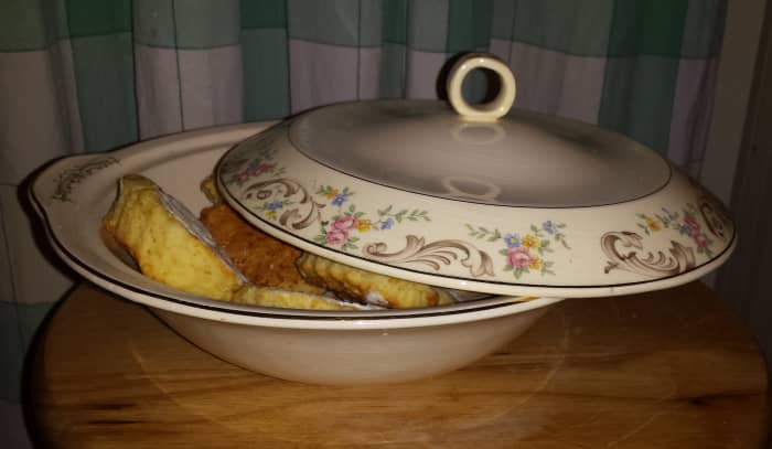 Photo of cream colored-covered porcelain serving dish with pink/blue/yellow floral pattern and gold filigree. Dish contains biscuits/scones.