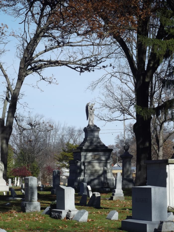 Photograph of old cemetery with large mausoleum in background featuring angel on top. Evergreen Cemetery, Muskegon, MI.
