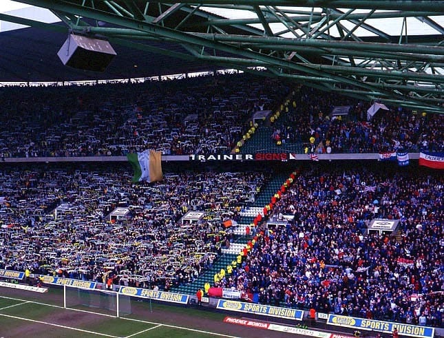 A photo showing both sets of fans at a match at Celtic Park. Celtic are on the left in green, Rangers are on the right in blue.