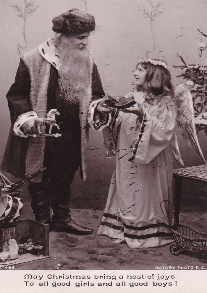 Santa Claus discusses Christmas present choices with an angel in this 1907 postcard. He already has the long white beard we are familiar with today.