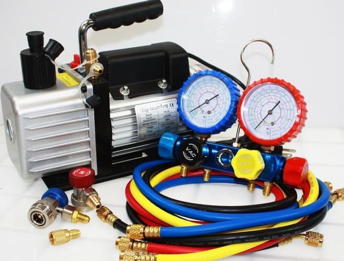 Typical portable HVAC vacuum pump with manifold gauges, hoses, and quick disconnect couplers for high/low fittings