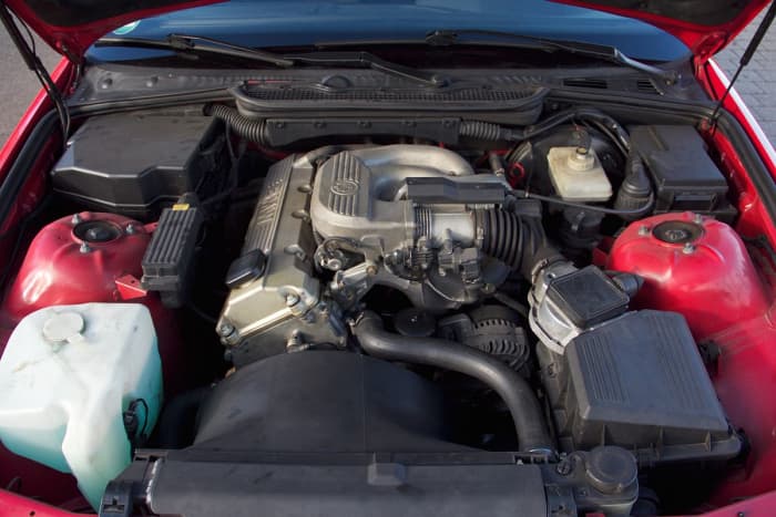 Radiator shroud, upper radiator hose, and coolant reservoir (left) are typical cooling system components.