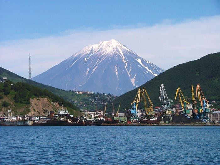 The Russian harbor of Petropavlovsk-Kamchatsky as seen from Avacha Bay. Snow-capped Mount Koryasky rises spectacularly in the background. This active volcano last erupted in 2009