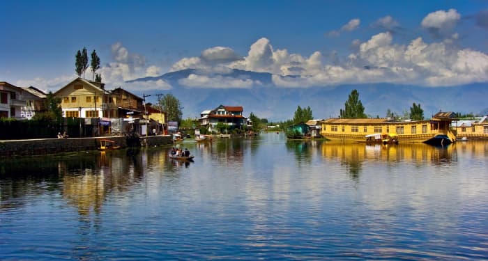 The beautiful Dal Lake reflecting the carved wooden balconies of the houseboats and the misty peaks of the Pir Panjal mountains.