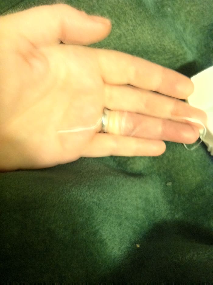 Begin to unwrap by pulling on the part of the string that went under the ring--pull away from your wrist toward the end of your finger