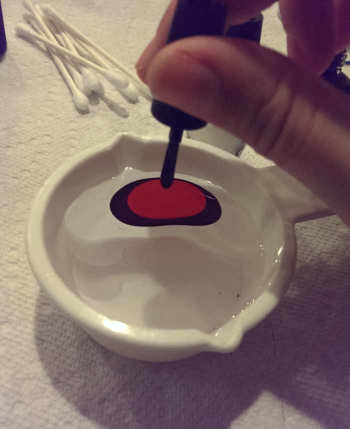 Dropping the colors carefully into the cup of room temperature water.