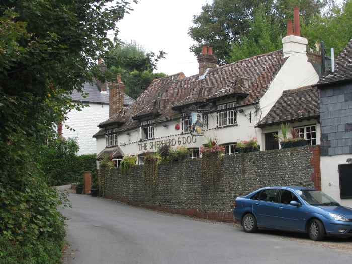 The Shepherd & Dog in Fulking, Sussex; a path to the right starts its ascent to the top of the Sussex Downs