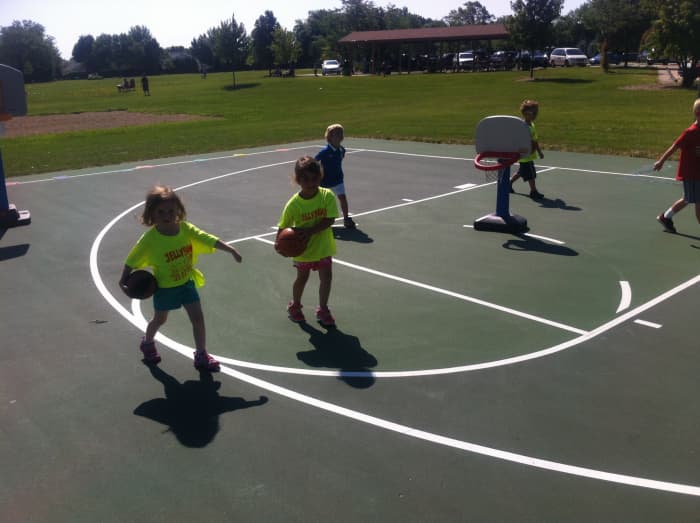 Young children practice dribbling a basketball without dribbling, carrying the basketball at their pockets with "strong arms" out to shield defenders..