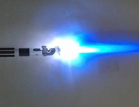 This miniature light saber consists of a simple LED and blue plastic straw. The battery is on the back of the card stock, with the LED and straw taped to the front of the card stock. A simple print of a light saber handle finishes the look!