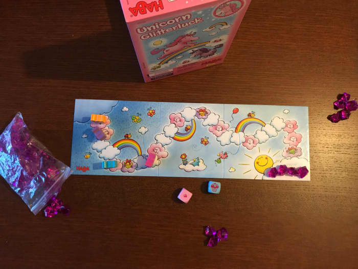 This is the board for Unicorn Glitterluck, showing the cloud course and the different types of clouds. The translucent purple gems are the cloud crystals. The blue die has rolled the dreaded muffin!