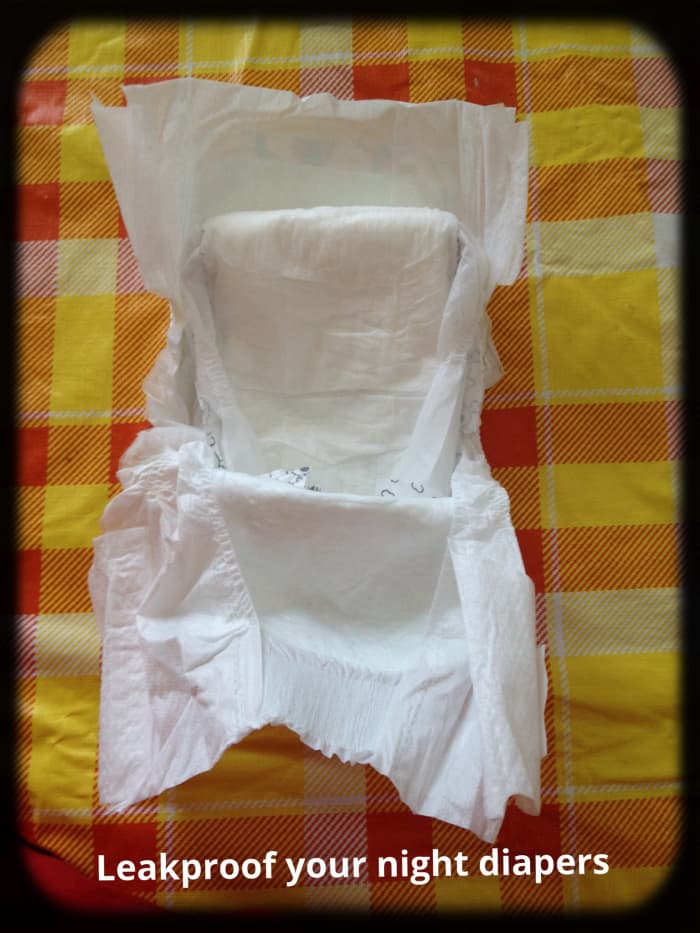 Tuck smaller diaper strip into front of larger diaper with folded side up. Keep it under waistband of larger diaper.