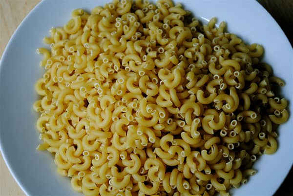 Because dried pasta hasn't absorbed the water yet, simply pour it into the bowl you will serve it in and fill it just below the point at which you want your cooked pasta serving to reach. It's inexact, but it works pretty well.
