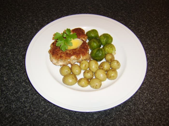 Schnitzel-style breaded turkey breast fillet is served with herb new potatoes and spiced Brussels sprouts.