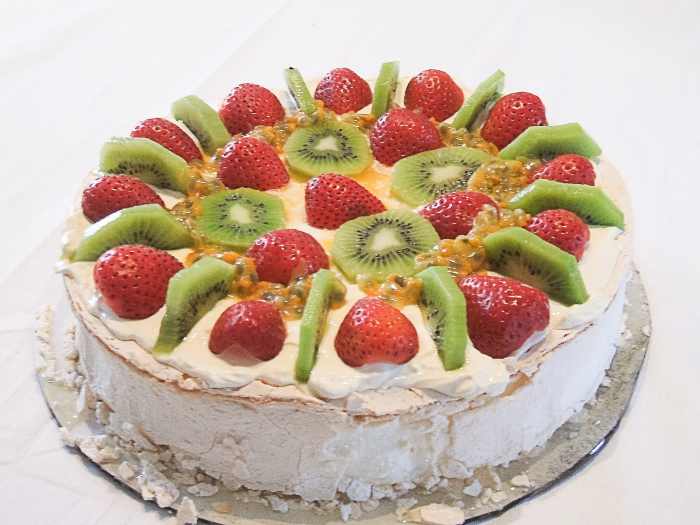 A pavlova dessert topped with strawberries, kiwi fruit and passion fruit