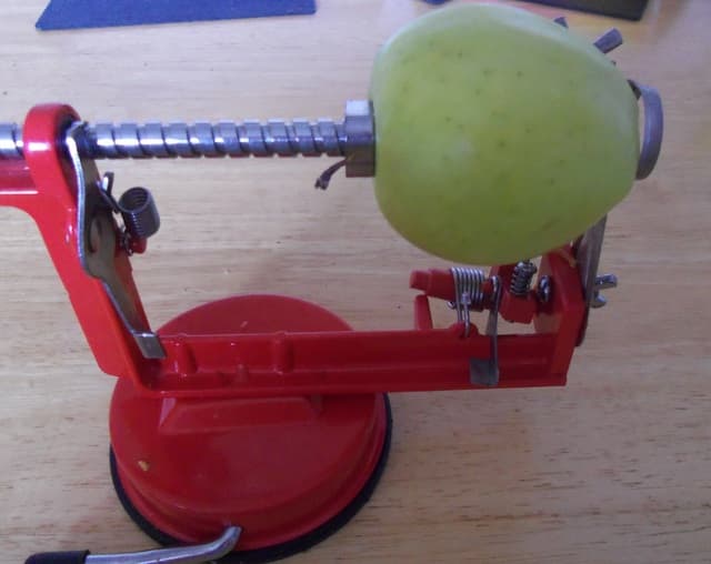 Place the apple on the prongs and turn the handle so that the apple moves against the blade.
