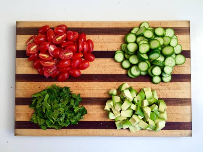 Slice the cucumbers, tomatoes, and avocado. Snip the mint leaves from the stems and tear leaves.