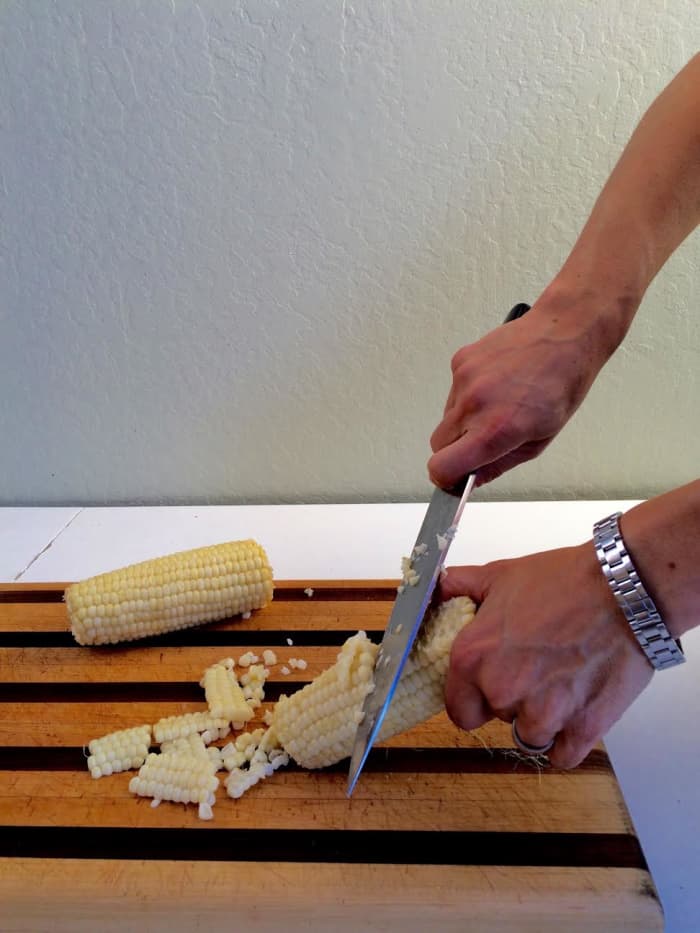 Use a knife to scrape the kernels from the cob. Be sure to watch your fingers and scrape downward toward the cutting board.