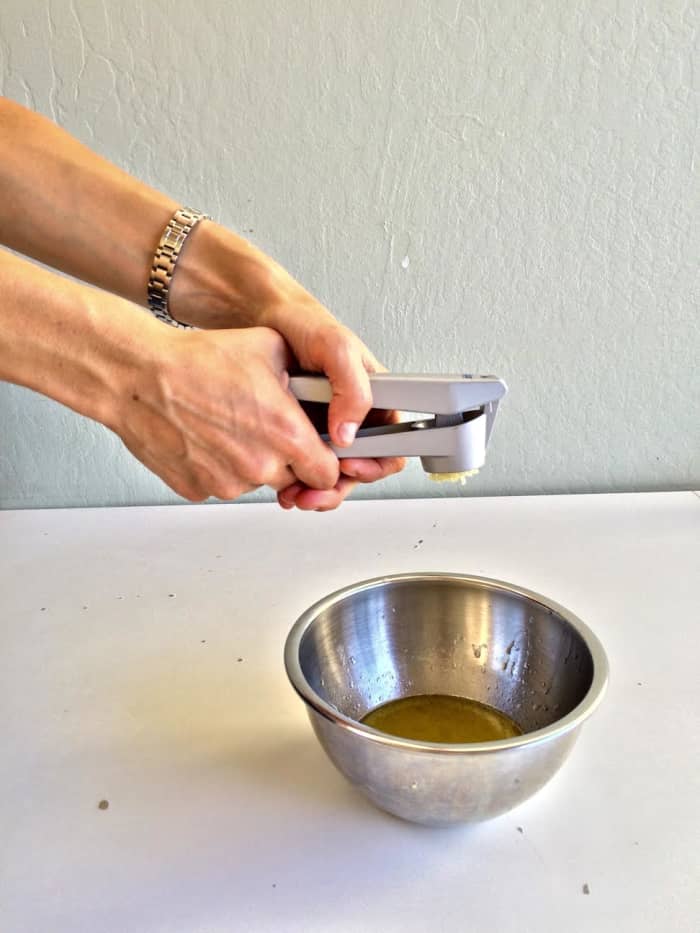 After adding the lime juice and olive oil to the mixing bowl, use a garlic press to crush the garlic directly into the bowl.