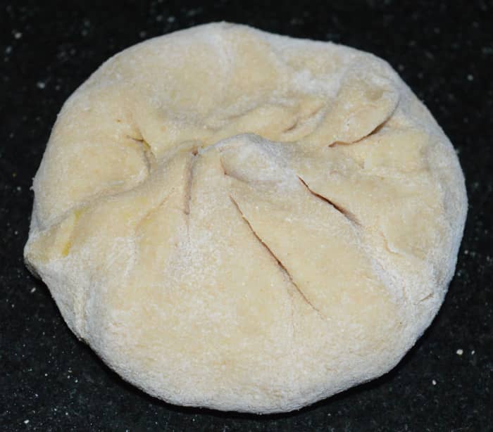 Step four: Divide the dough in many equal portions of a lemon size. Likewise, divide the stuffing in equal number of portions. Take one such dough portion. Shape it like a patty. Roll it into a disc of 3 inch diameter.