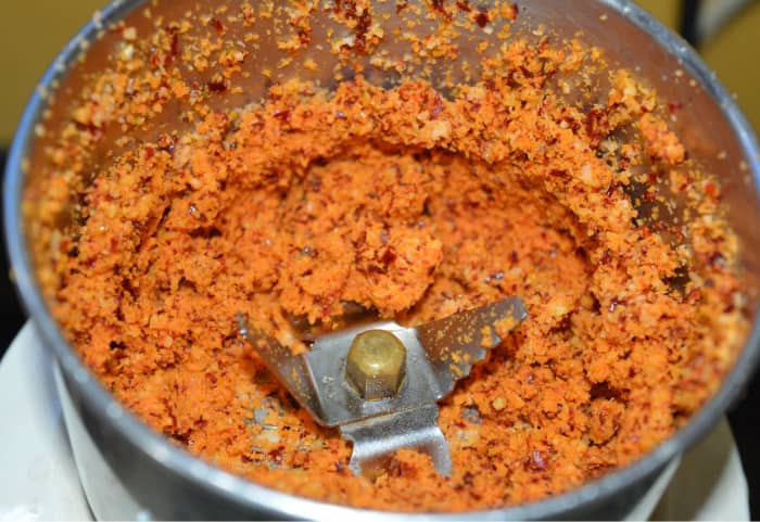 Step two: Put grated coconut into a mixer or blender. Add 1/4 teaspoon mustard seeds and broken dry red chilies. Pulse a few times to make a rough powder. Set aside.