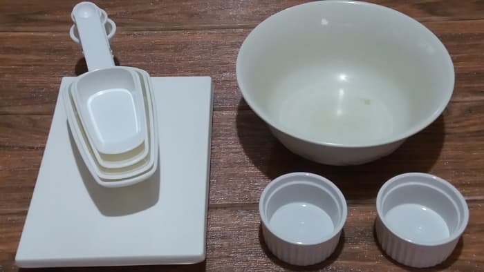 Utensils for marinating the chicken: measuring cups, two small bowls, one large bowl, one plate
