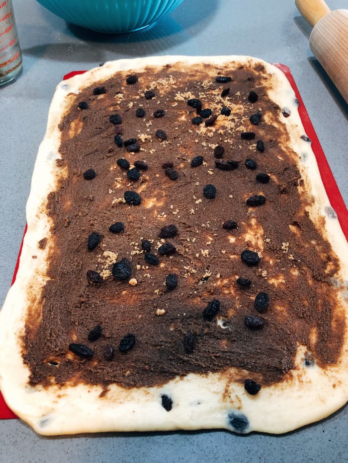 Brush melted butter on the dough, sprinkle ground cinnamon and brown sugar. Add more raisins if desired.