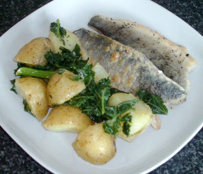 Pan fried sea bass fillets are served with boiled potatoes and kale in a rich and tasty turmeric and tarragon butter sauce
