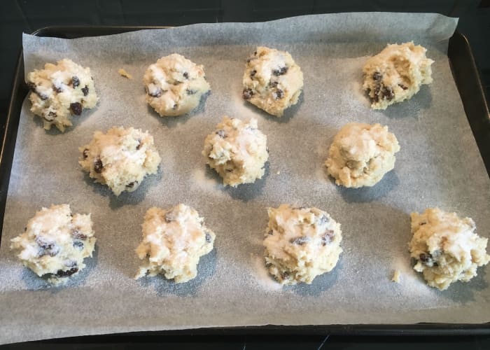 Uncooked rock cakes spaced out on a baking sheet lined with baking parchment. Ready for the oven.