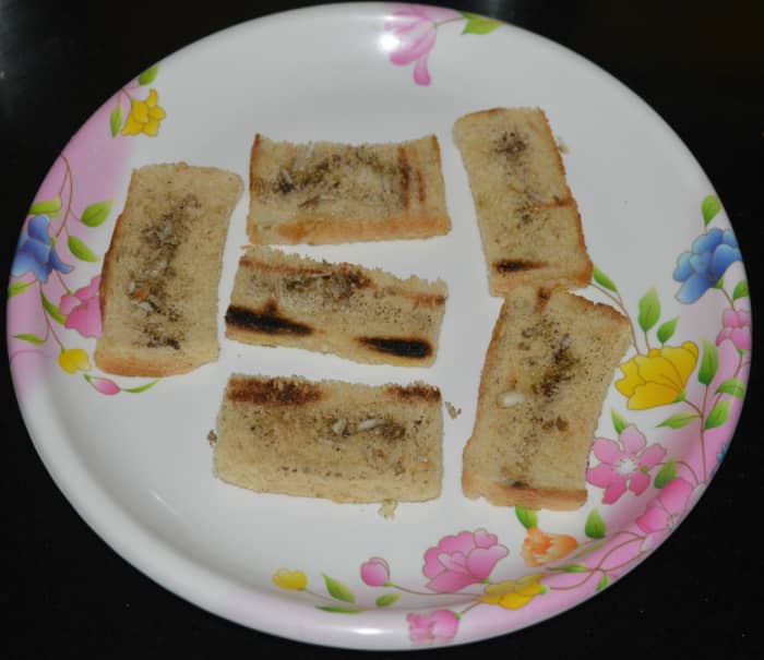Step two: Remove the edges of the bread slices. Cut each slice in half. Grill the bread in the oven until they become crispy. Apply olive oil, salt, and pepper powder on both the sides